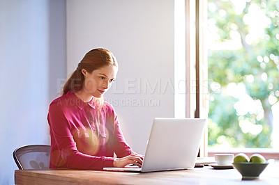 Buy stock photo Shot of a young woman working on a laptop at a desk in an office