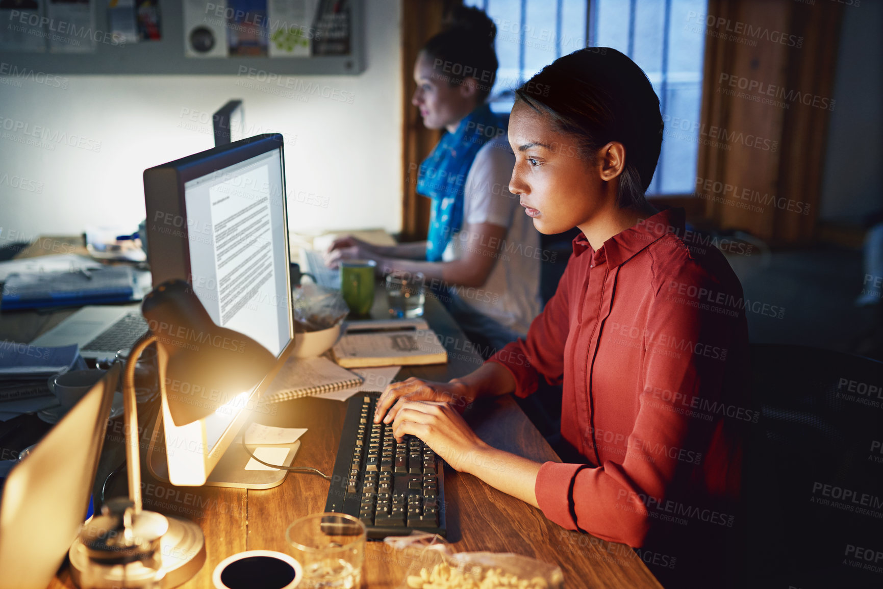 Buy stock photo Shot of a young woman working on a laptop in an office in the evening