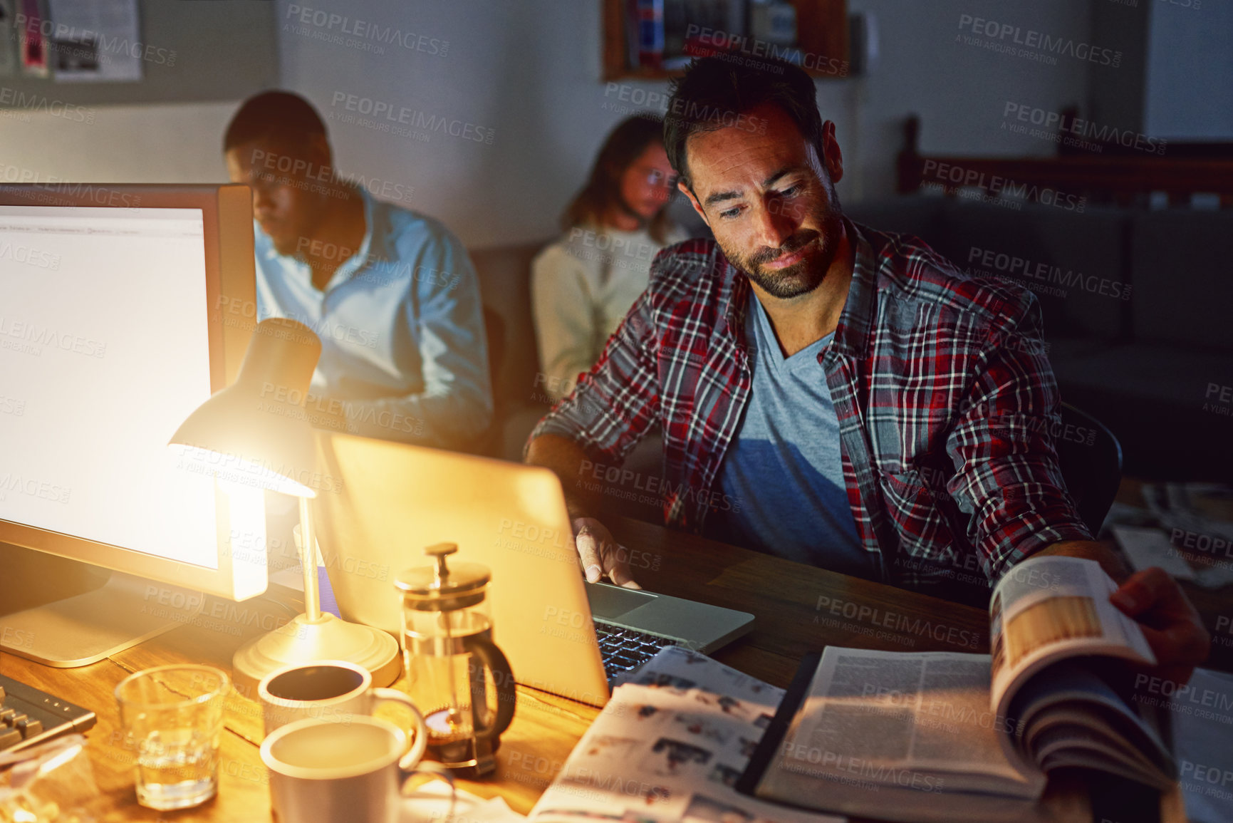 Buy stock photo Laptop, night and man reading book in office for research, story review and headline inspiration. Editor, computer or person in creative startup for overtime, magazine publication and coworking