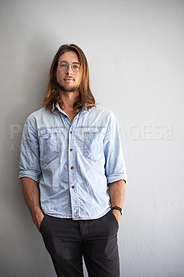 Buy stock photo Portrait of a smiling young man standing with his arms crossed against a gray background