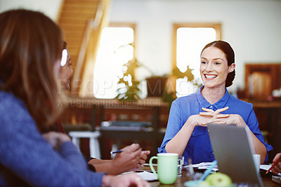 Buy stock photo Shot of a smiling young woman talking with colleagues while sitting at a table in office
