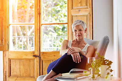 Buy stock photo Portrait of a smiling mature woman relaxing on a chair at home