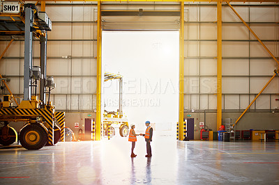 Buy stock photo Shot of two warehouse workers shaking hands together inside of a large warehouse