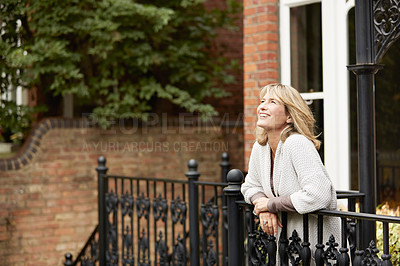 Buy stock photo Shot of a mature woman leaning against the railing of her front porch