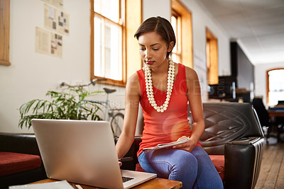 Buy stock photo Shot of a young professional working on a laptop in an office