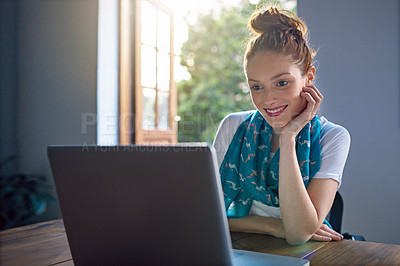 Buy stock photo Shot of a young woman sitting by an open door in an office working on a laptop