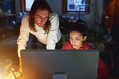 Buy stock photo Shot of two colleagues talking over a computer in an office late in the evening