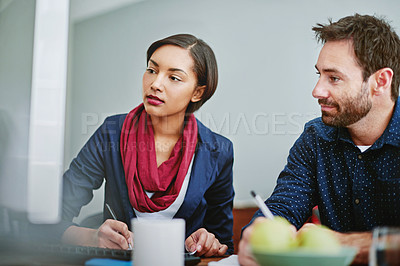 Buy stock photo Shot of two colleagues talking together while sitting at a desk in an office