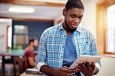 Buy stock photo Shot of a young man using a digital tablet in an office