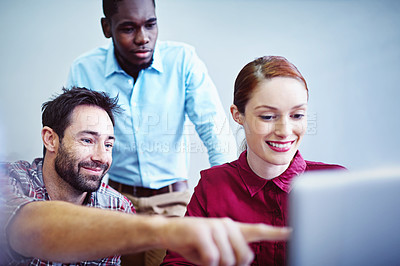 Buy stock photo Shot of a group of businesspeople working together on a laptop in an office