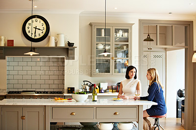 Buy stock photo Shot of two young woman having a chat while sitting in the kitchen