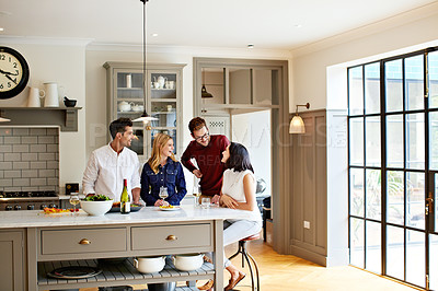 Buy stock photo Shot of two young couples having a chat while chilling in the kitchen