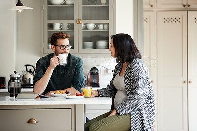 Buy stock photo Shot of a young man having breakfast with his pregnant wife in the kitchen