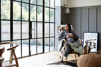Buy stock photo Shot of an attractive and pregnant young woman relaxing on a rocking chair