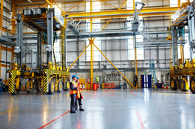 Buy stock photo Shot of two male dock workers talking together inside of a large warehouse