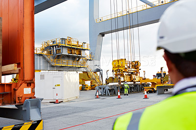 Buy stock photo Over the shoulder shot of a male construction worker on a commercial dock