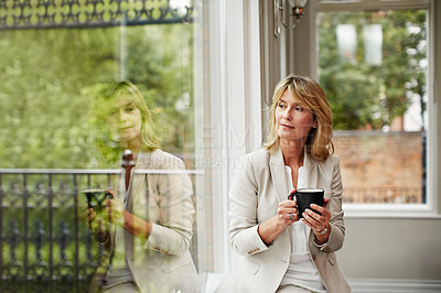 Buy stock photo Shot of a mature businesswoman sending a text message while sitting next to a window in her home