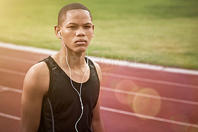 Buy stock photo Portrait of an athletic young man listening to music while standing on the track