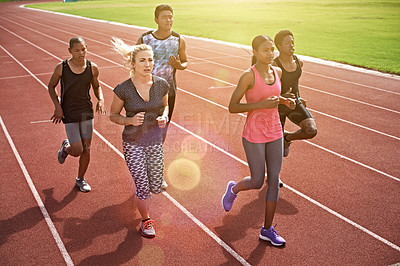 Buy stock photo Shot of a group of young athletes out running on the track