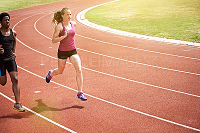 Buy stock photo Shot of two young athletes racing on the track