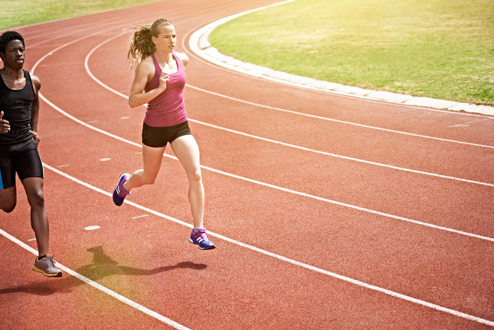 Buy stock photo Shot of two young athletes racing on the track