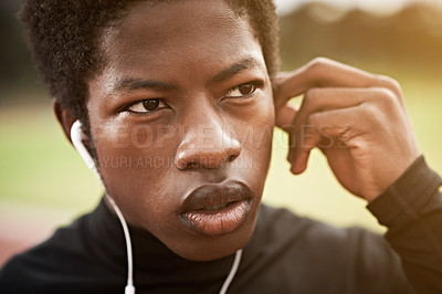 Buy stock photo Cropped shot of a young athlete listening to music while out on the track