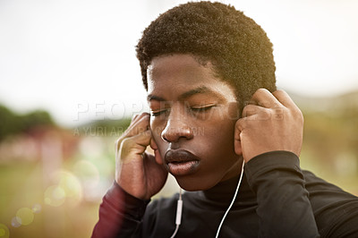 Buy stock photo Cropped shot of a young athlete listening to music while out on the track