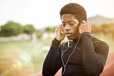 Buy stock photo Cropped shot of a young athlete listening to music while out on the track