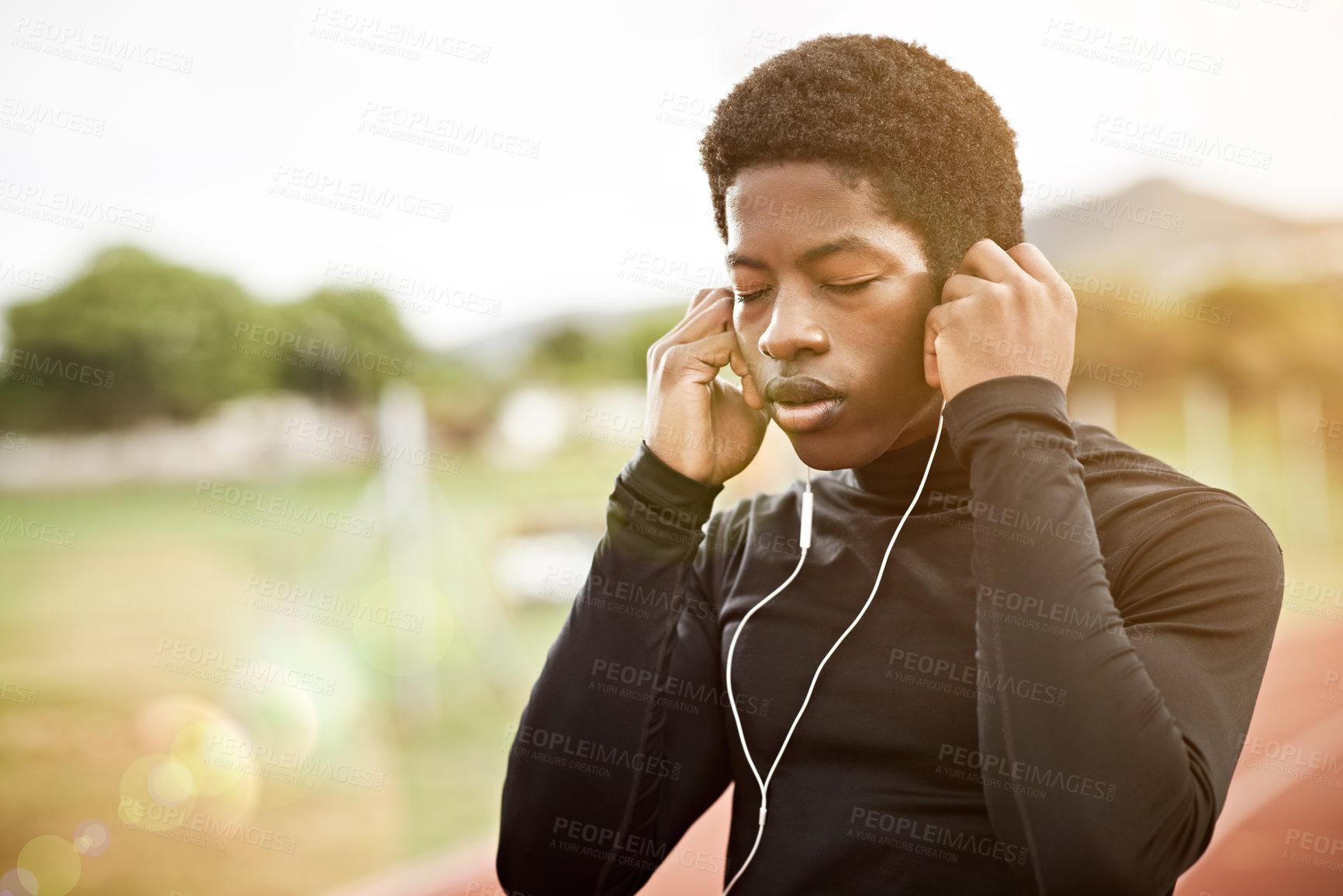 Buy stock photo Cropped shot of a young athlete listening to music while out on the track