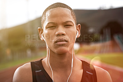 Buy stock photo Cropped shot of a young athlete listening to music while out on the track