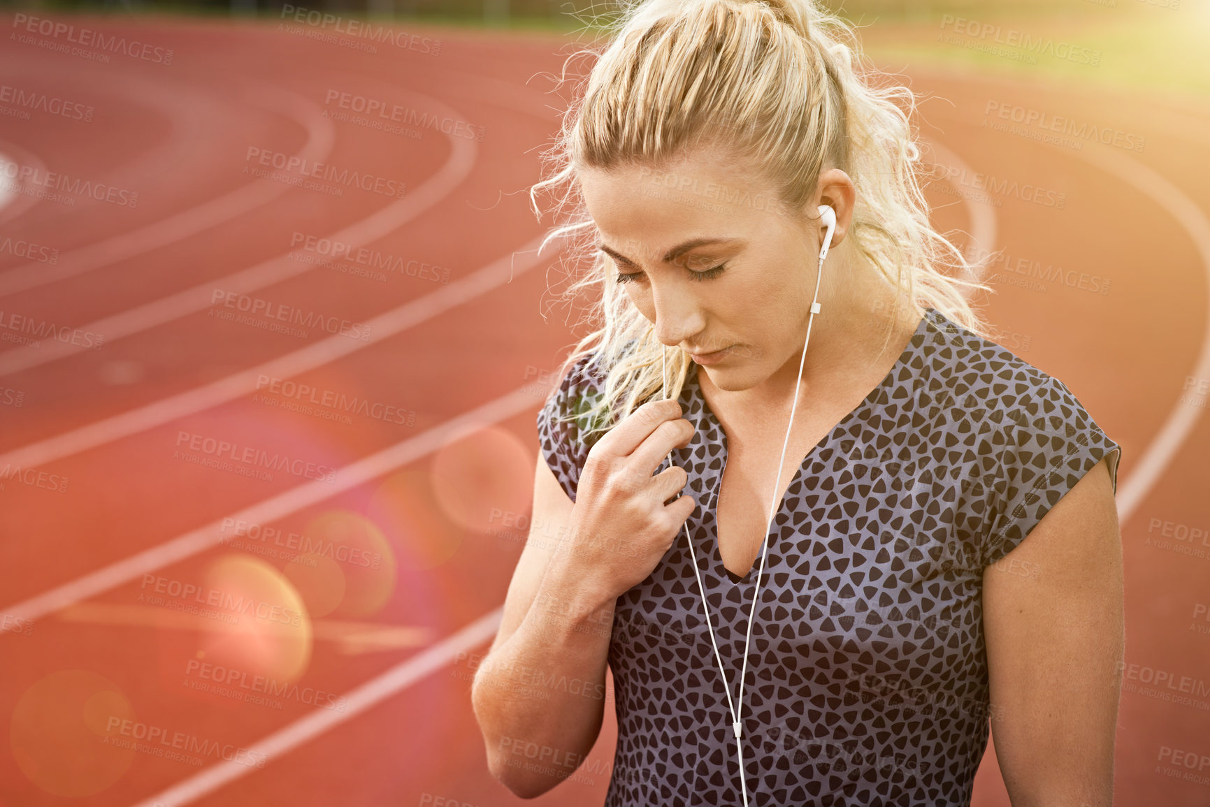 Buy stock photo Cropped shot of a young athlete listening to music while out on the track