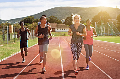 Buy stock photo Shot of a group of young athletes out running on the track