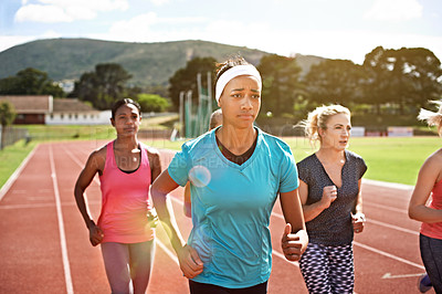 Buy stock photo Shot of a group of young athletes out running on the track