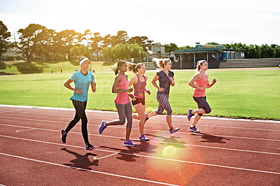 Buy stock photo Shot of a group of young athletes out running on the track