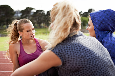 Buy stock photo Shot of a group of young athletes sitting out on the track after a run