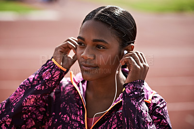 Buy stock photo Cropped shot of a young athlete listening to music while out on the track