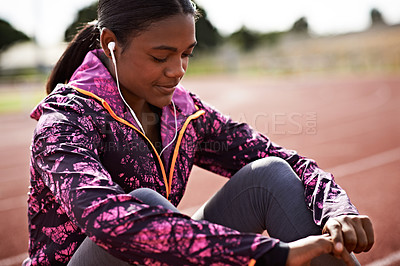 Buy stock photo Cropped shot of a young athlete listening to music while out on the track