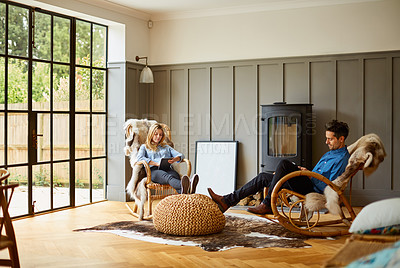 Buy stock photo Shot of a couple using digital tablets while relaxing on rocking chairs at home