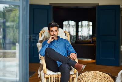 Buy stock photo Shot of a young man using a digital tablet while relaxing on a rocking chair at home