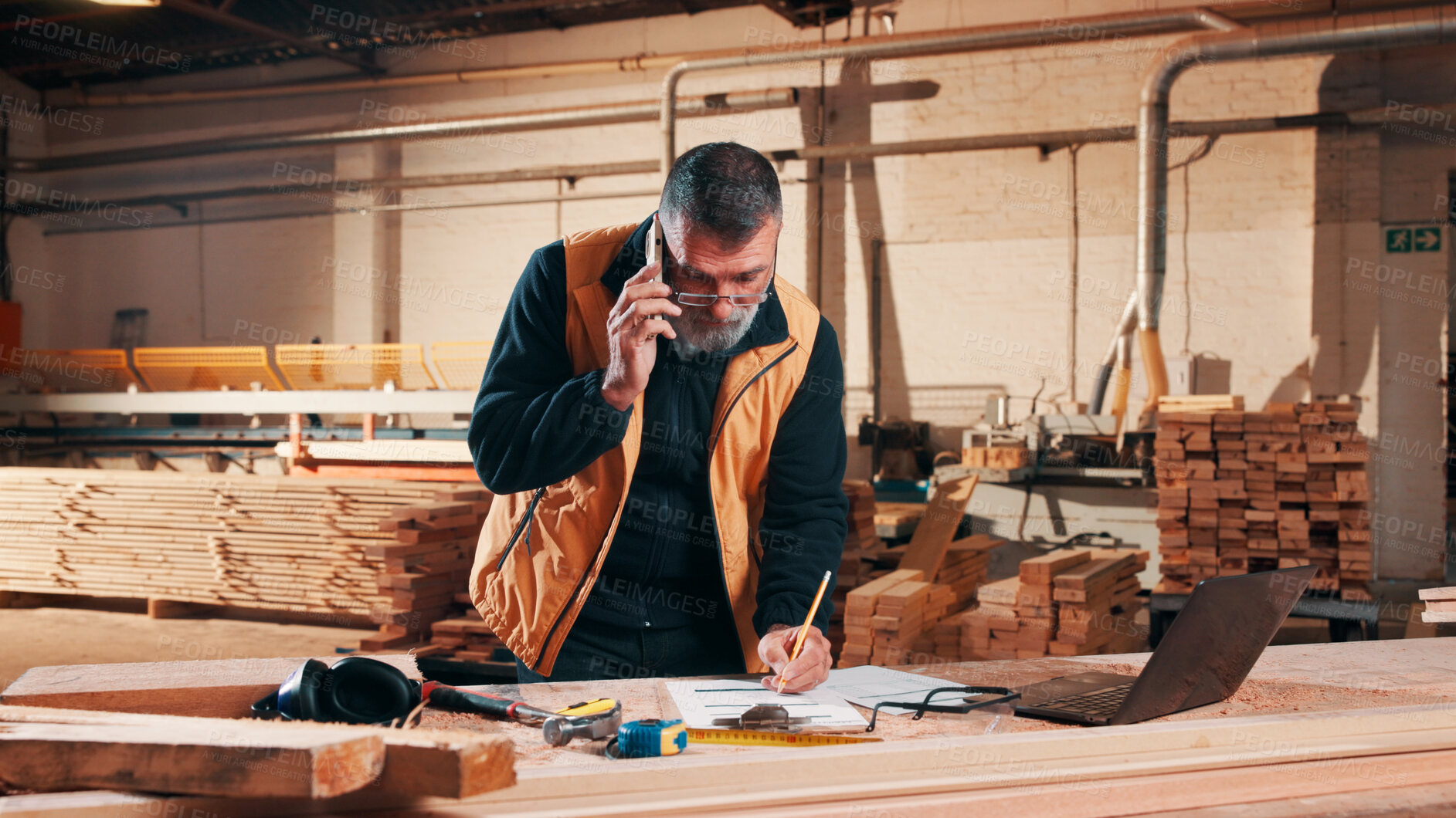 Buy stock photo Carpenter, phone call and man on laptop in workshop for planning, schedule or writing quote. Warehouse, mature person or carpentry with technology for woodwork or furniture production with paperwork