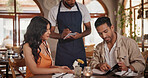 Server, menu and couple in restaurant for date, connection or bonding on weekend together. Discussion, food and waiter with man and woman for decision on dinner, meal or supper order in diner.