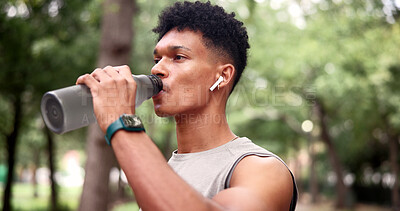 Buy stock photo Man, fitness and drinking with water in nature for workout rest, outdoor break or recovery. Active, male person or runner with bottle, earphones or mineral liquid for training music or songs in park