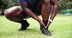 Outdoor, man and ankle pain with hands, fitness and grass field for exercise and workout with muscle tension. Person, athlete and runner with accident, overworked joint and burnout from training