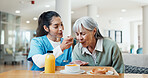 Assisted living, breakfast and nurse feeding old woman in dining room for help, care or support. Eating, food and retirement with senior person in home for healthy diet, nutrition or wellness