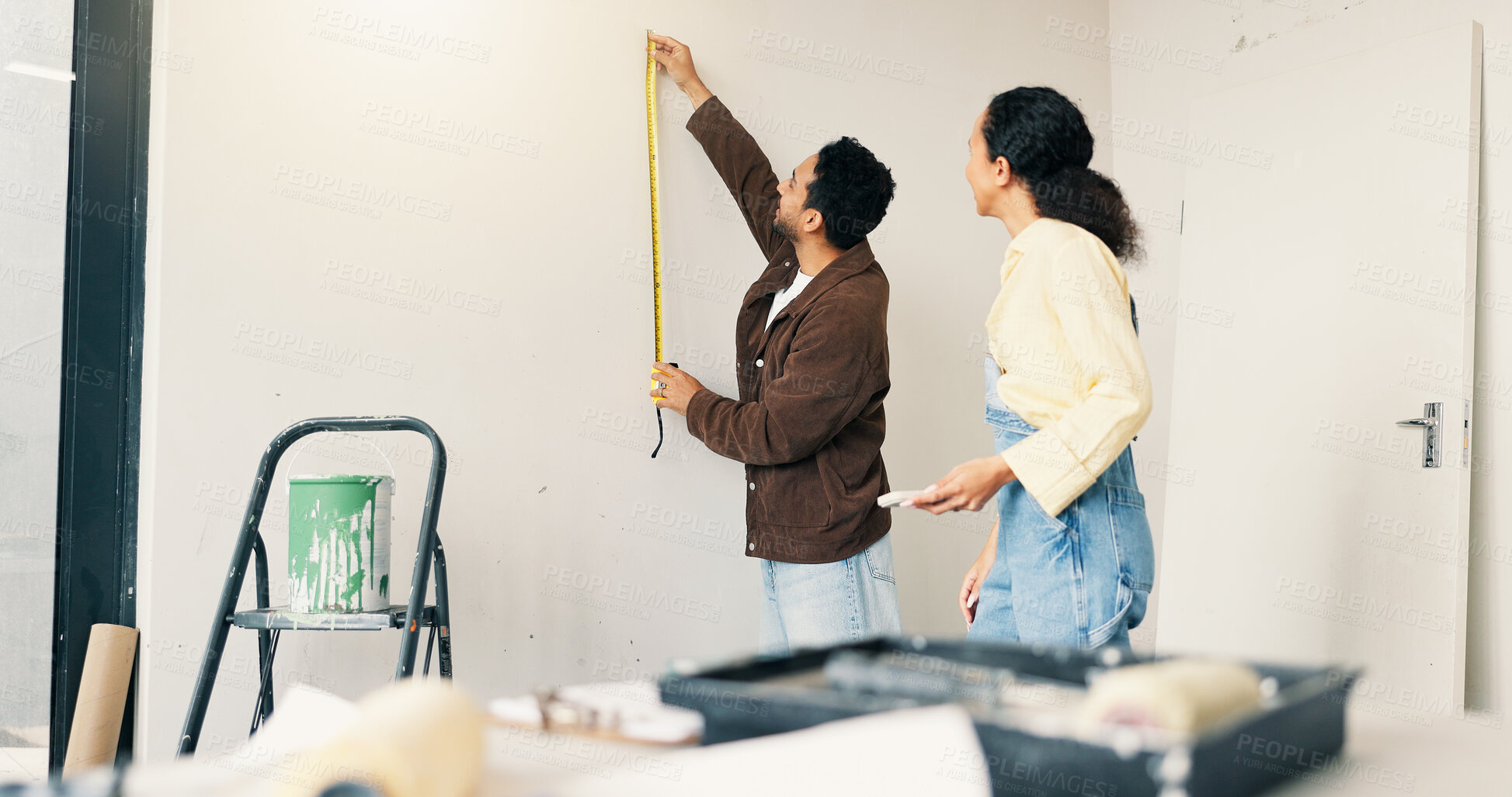 Buy stock photo Measuring, tape and couple in new home for renovation, maintenance or property development. Tool, real estate and man with woman for precision on wall for construction repairs in apartment together.