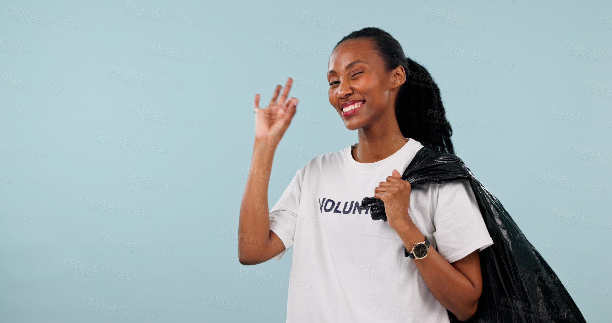 Buy stock photo Volunteer, portrait and black woman with okay sign, happy and trash or cleaning garbage in studio. Non profit, community service and space for wink, success and plastic bag on blue background