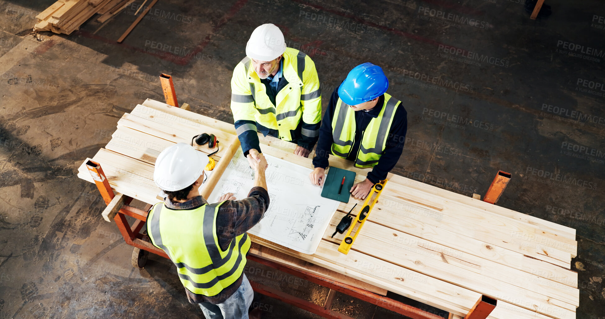 Buy stock photo Above, engineer and handshake at construction site with blueprint, development deal or agreement. Architect team, people or shaking hands with floor plan for cooperation, safety approval and top view