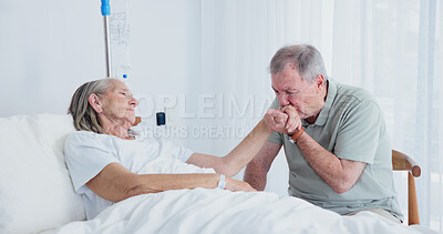 Buy stock photo Senior, couple or kiss with patient on bed in nursing home for medical support together. Elderly, man and woman holding hands on IV drip for healthcare, empathy or understanding in old age house