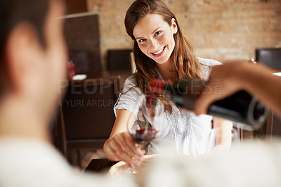 Buy stock photo Woman, date and pouring wine at restaurant while happy with love, care and commitment to partner. Couple, bottle and drinking to romantic connection, anniversary or dining with smile in relationship
