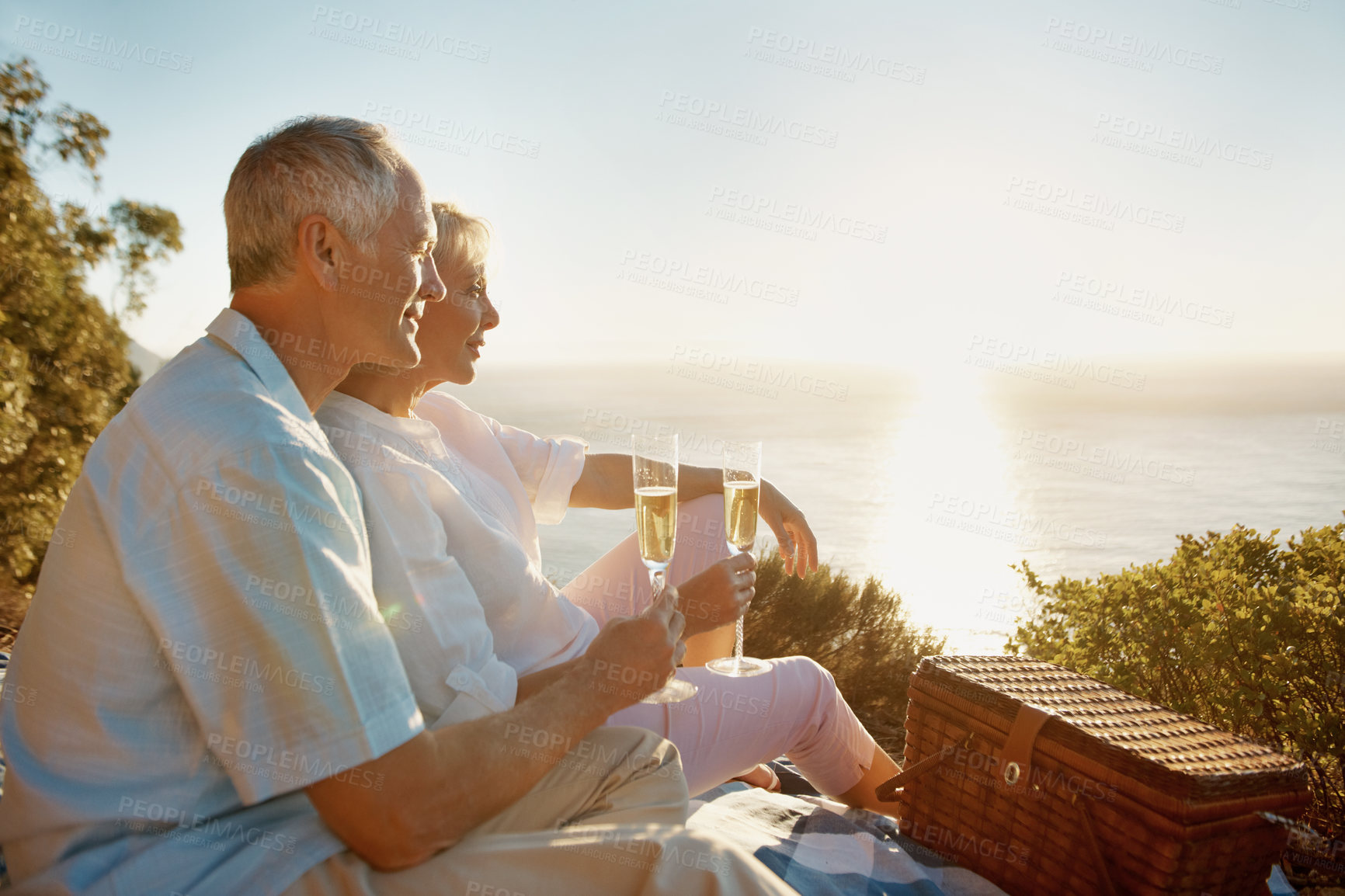 Buy stock photo Picnic, old couple and sunset with champagne for support, bonding together and love in healthy relationship. Nature, senior man and woman with wine for happy, marriage and care on weekend holiday